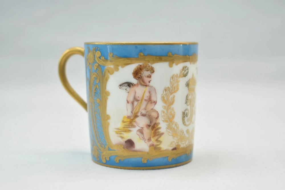 A six-piece set of white and sky-blue French porcelain demitasse cups and saucers decorated with gilded royal monograms, cherubs, and leaf borders. View IX