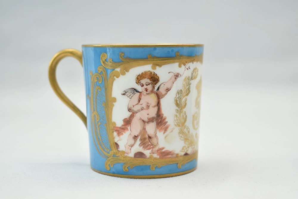 A six-piece set of white and sky-blue French porcelain demitasse cups and saucers decorated with gilded royal monograms, cherubs, and leaf borders. View X