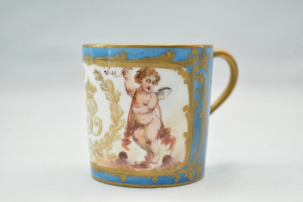 A six-piece set of white and sky-blue French porcelain demitasse cups and saucers decorated with gilded royal monograms, cherubs, and leaf borders. View XI