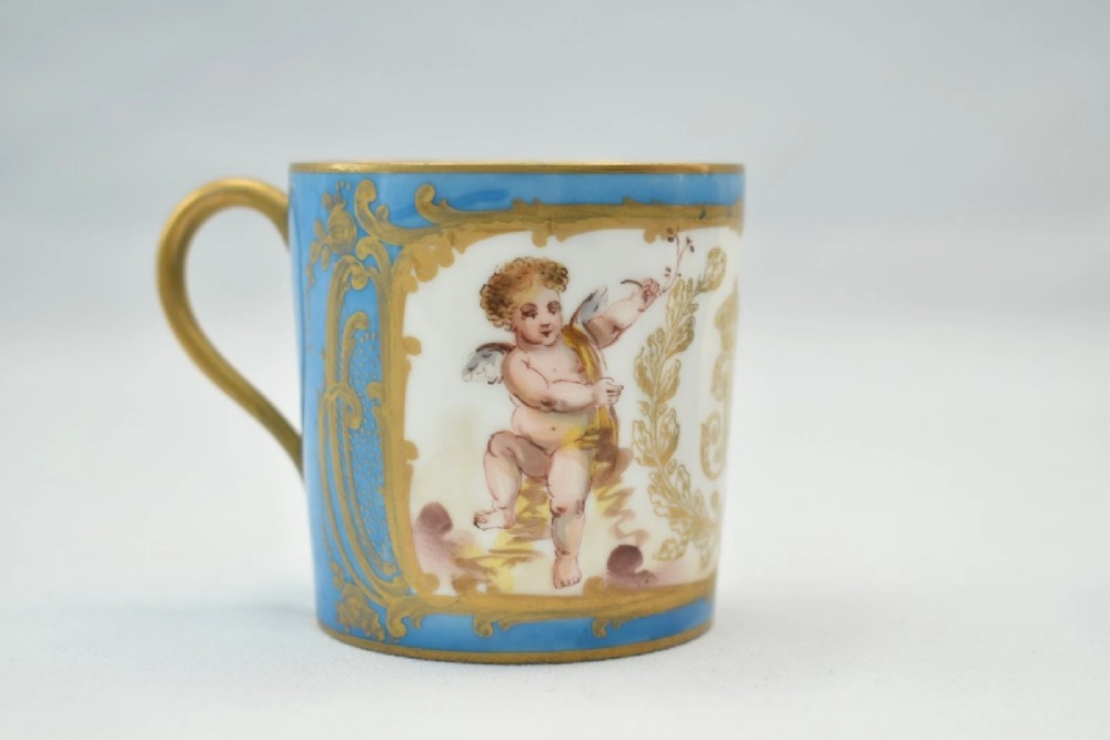 A six-piece set of white and sky-blue French porcelain demitasse cups and saucers decorated with gilded royal monograms, cherubs, and leaf borders. View XII
