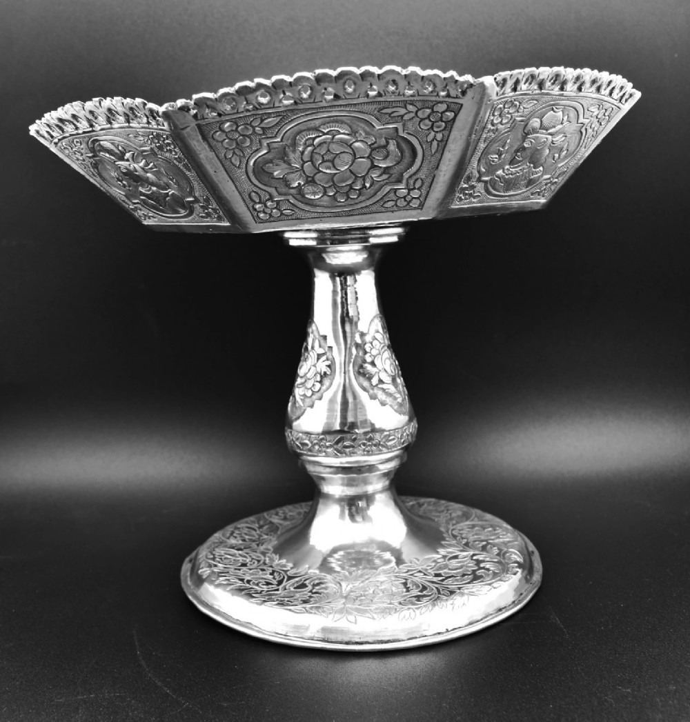 An octagonal antique silver repousse tazza featuring a central raised portrait medallion, intricate chased foliate side panels, and a pierced scalloped border. View X
