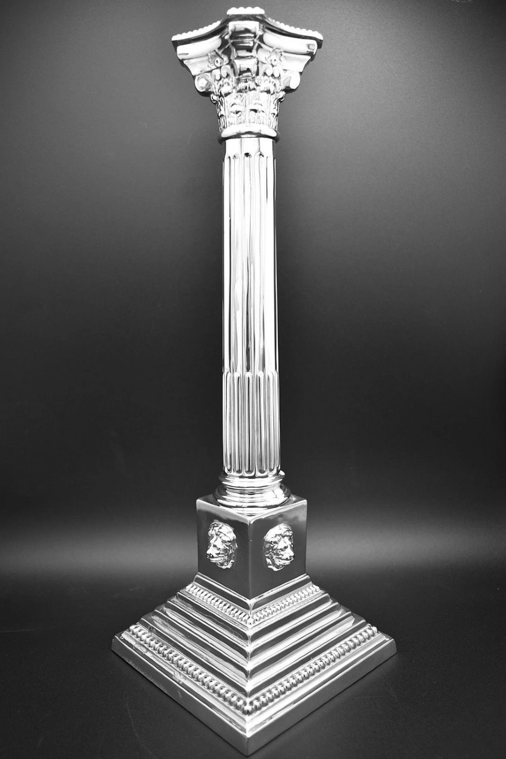 A pair of sterling silver candlesticks featuring fluted Corinthian columns, acanthus leaf capitals, lion mask motifs, and stepped square bases with beaded edging. View II