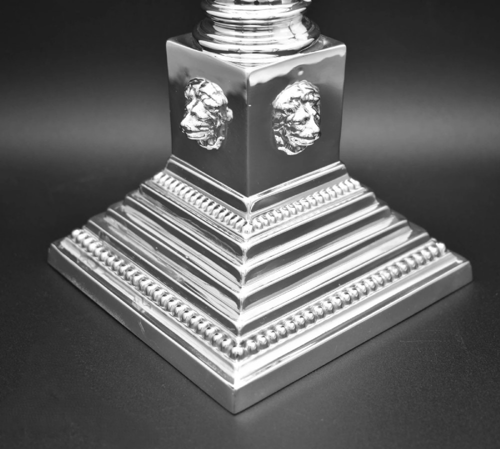 A pair of sterling silver candlesticks featuring fluted Corinthian columns, acanthus leaf capitals, lion mask motifs, and stepped square bases with beaded edging. View III