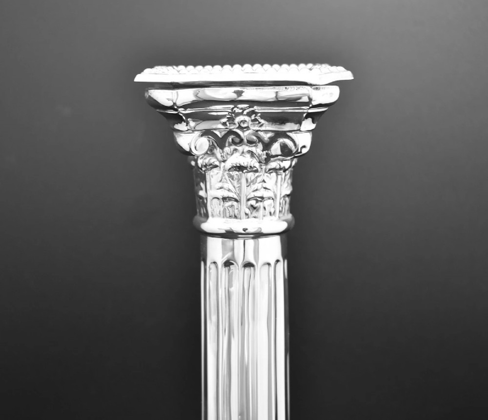 A pair of sterling silver candlesticks featuring fluted Corinthian columns, acanthus leaf capitals, lion mask motifs, and stepped square bases with beaded edging. View V