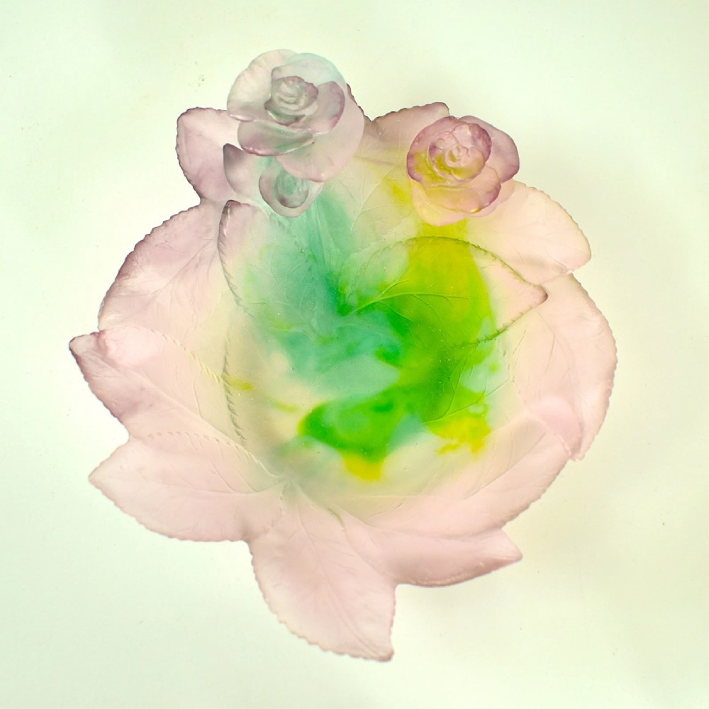 A Daum France pate de verre crystal rose bowl shaped like a pink blossom with green leaves, displayed alongside its original presentation box. View II