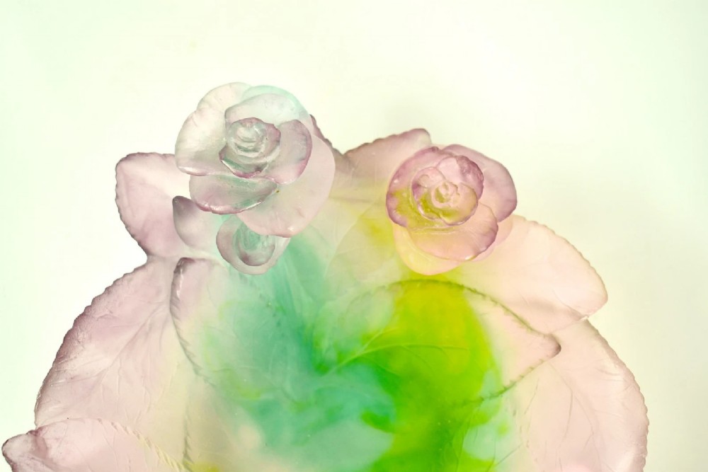 A Daum France pate de verre crystal rose bowl shaped like a pink blossom with green leaves, displayed alongside its original presentation box. View III