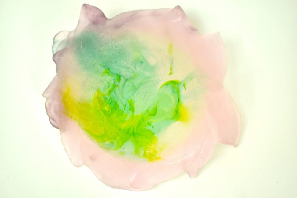 A Daum France pate de verre crystal rose bowl shaped like a pink blossom with green leaves, displayed alongside its original presentation box. View IV