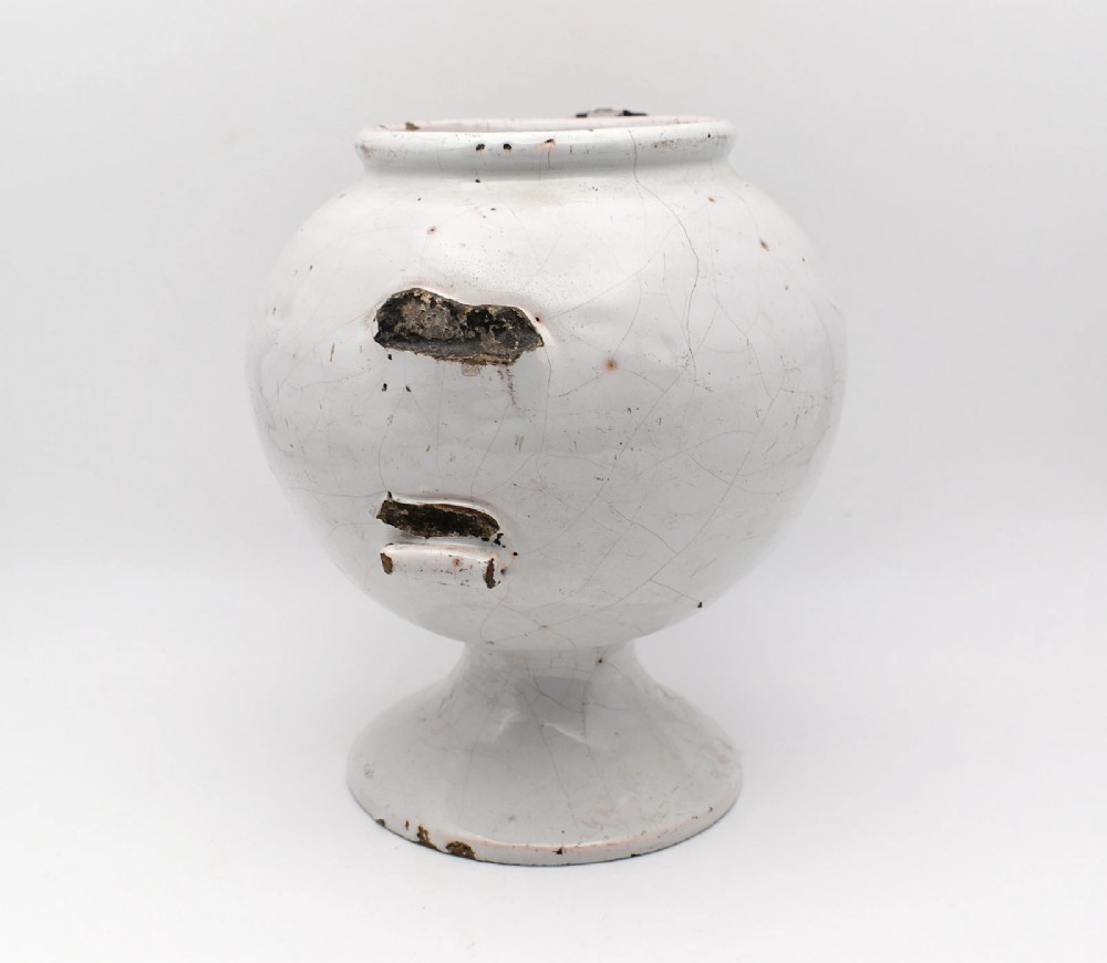 An 18th-century English delftware apothecary wet drug jar decorated in cobalt blue and white with a pouring spout, footed base, cherub motif, and the inscription S: BALSAM. View III