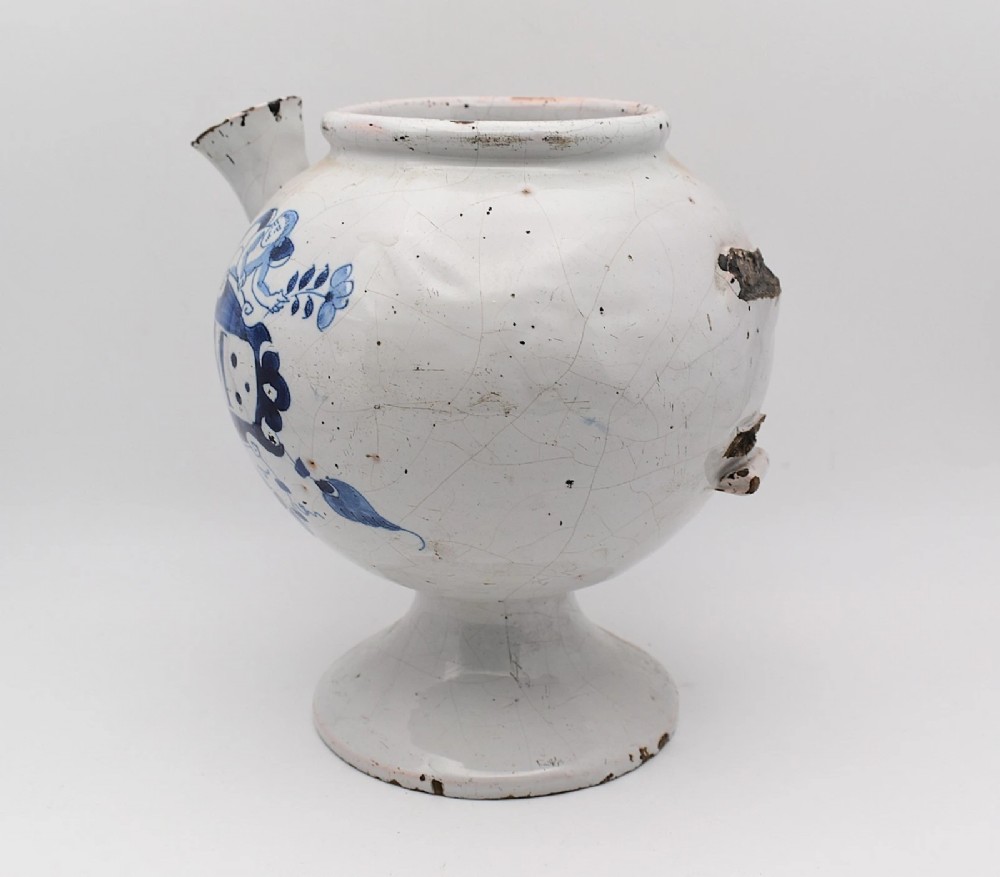 An 18th-century English delftware apothecary wet drug jar decorated in cobalt blue and white with a pouring spout, footed base, cherub motif, and the inscription S: BALSAM. View IV