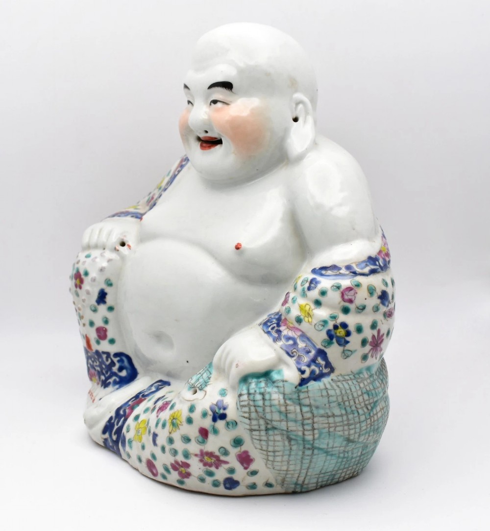 A seated twentieth-century Chinese famille rose porcelain figure of a laughing Budai draped in a floral enamelled robe. View II