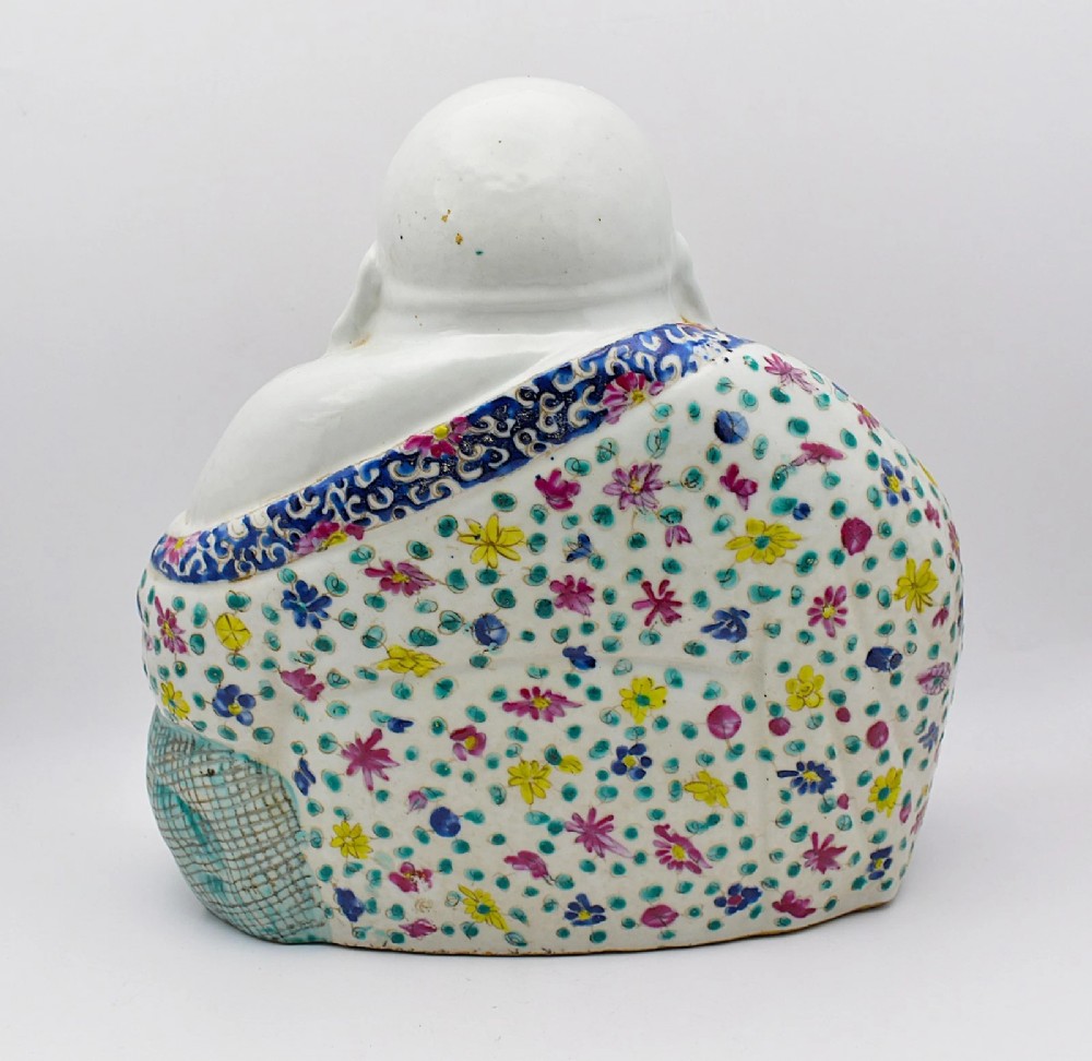 A seated twentieth-century Chinese famille rose porcelain figure of a laughing Budai draped in a floral enamelled robe. View III