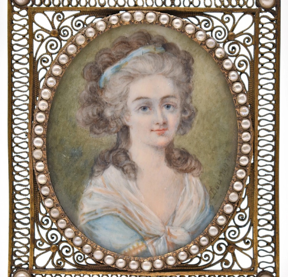 An 18th-century oval watercolour portrait miniature depicting a woman with curled hair, housed within a seed pearl bezel and a gilt filigree rectangular frame. View II
