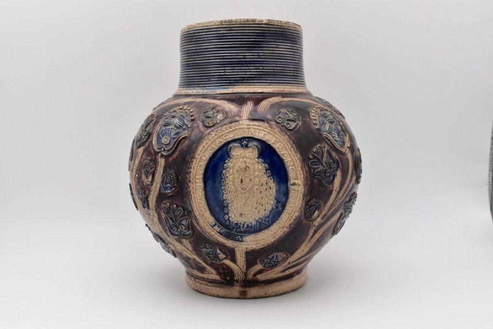 A seventeenth-century salt-glazed Westerwald stoneware jug decorated with cobalt blue and manganese violet glazes, featuring a central medallion with a royal portrait profile.