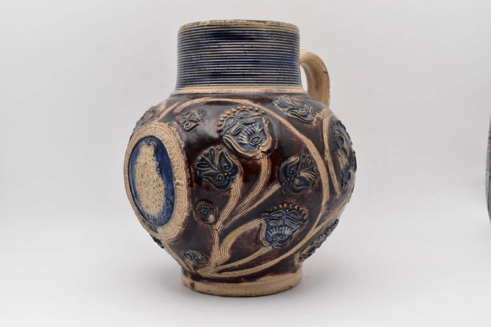 A seventeenth-century salt-glazed Westerwald stoneware jug decorated with cobalt blue and manganese violet glazes, featuring a central medallion with a royal portrait profile. View II