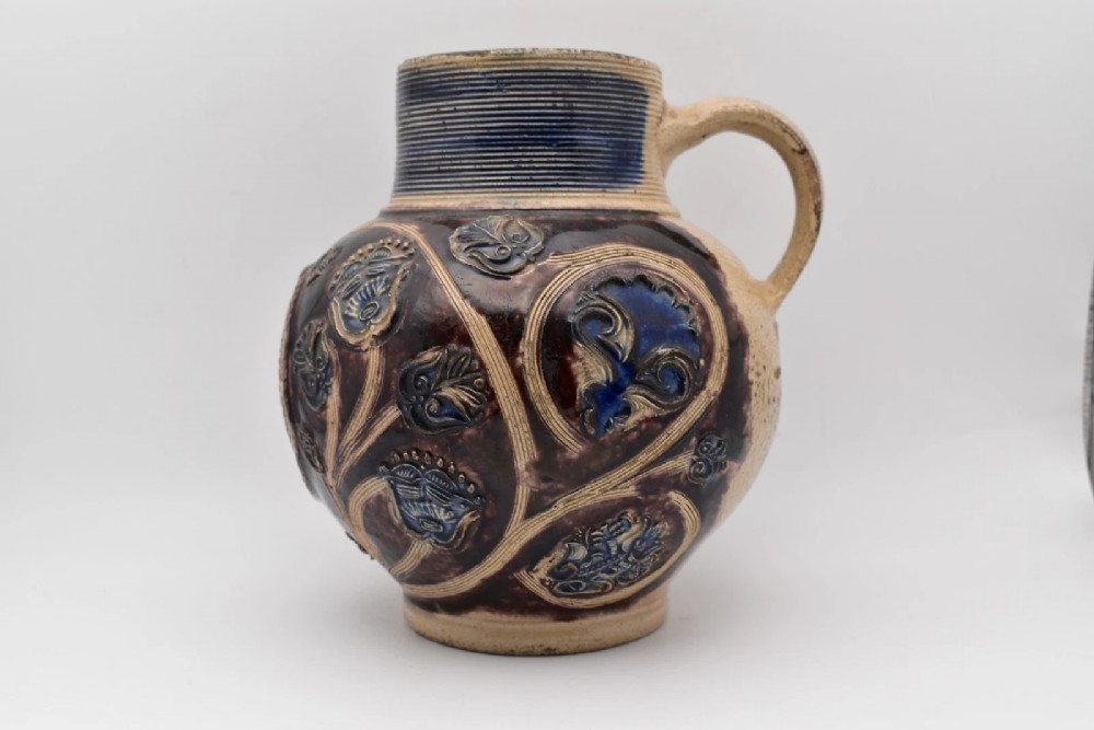A seventeenth-century salt-glazed Westerwald stoneware jug decorated with cobalt blue and manganese violet glazes, featuring a central medallion with a royal portrait profile. View III