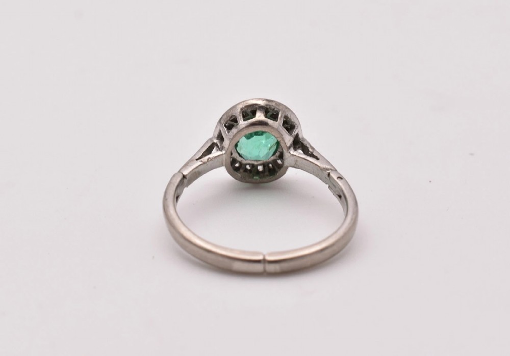 An oval green emerald set at the centre of a white gold cluster ring surrounded by small diamonds with an adjustable band. View VII
