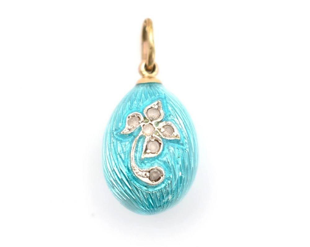 A turquoise guilloche enamel egg pendant decorated with a rose-cut diamond floral motif and topped with a gold suspension bail.