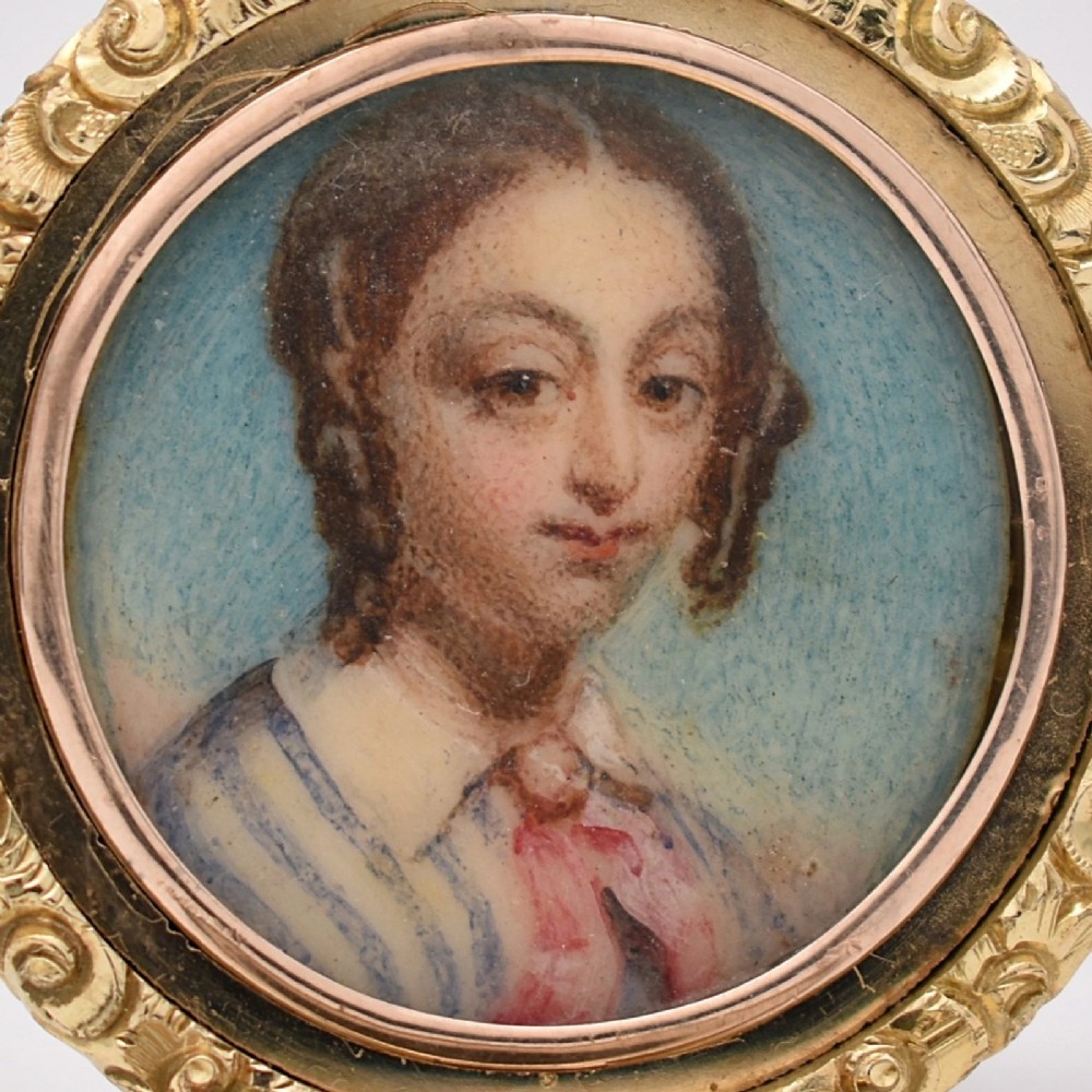 A circular gold locket pendant featuring a hand-painted portrait of a woman with dark hair against a light blue background. View III