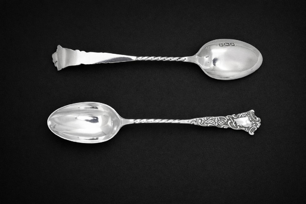 A set of twelve silver teaspoons with twisted stems and matching sugar tongs arranged inside a fitted burgundy velvet-lined case. View III