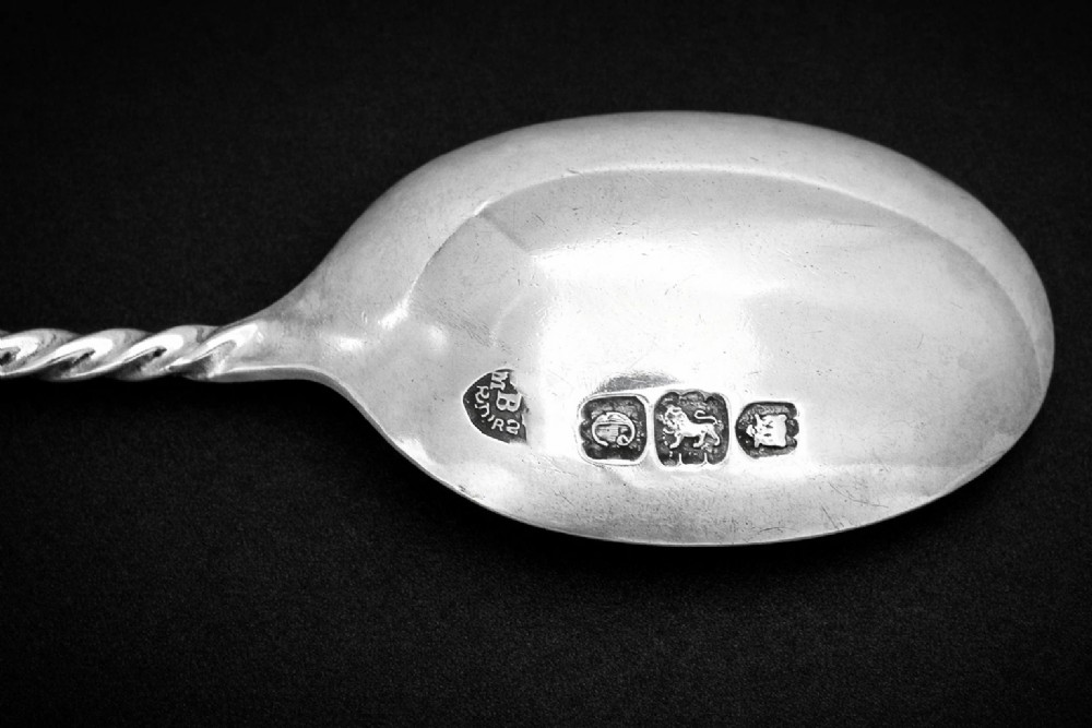 A set of twelve silver teaspoons with twisted stems and matching sugar tongs arranged inside a fitted burgundy velvet-lined case. View IV