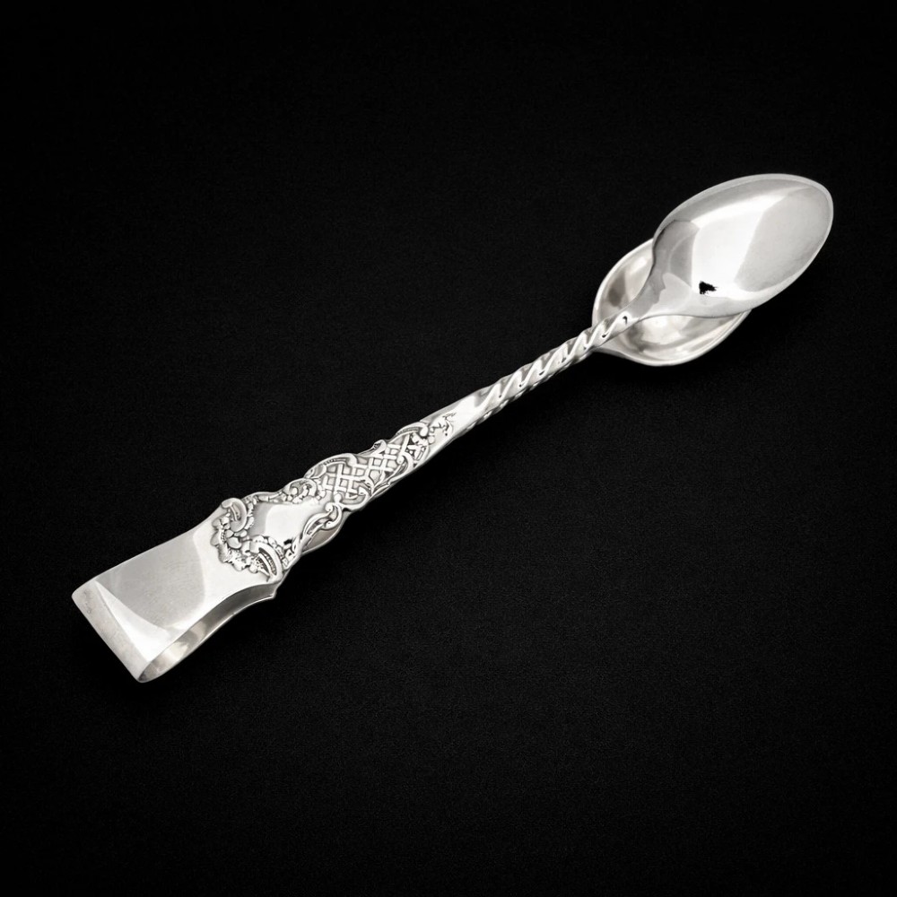A set of twelve silver teaspoons with twisted stems and matching sugar tongs arranged inside a fitted burgundy velvet-lined case. View V