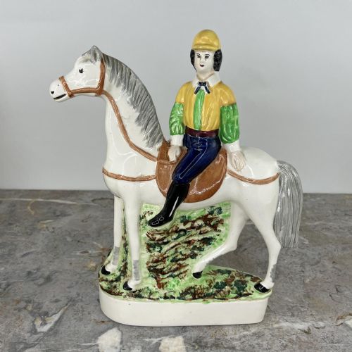 fig 4. A pair of hand-painted earthenware Staffordshire flatback figures depicting jockeys wearing yellow and green silks mounted on white horses.