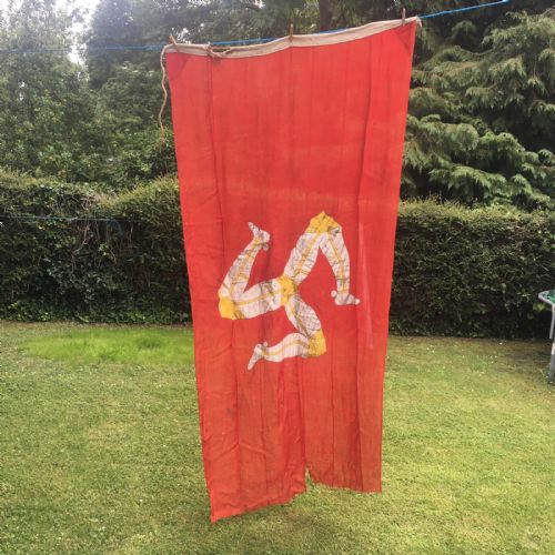 fig 1. A 1930s red cotton flag featuring the stitched white and yellow Triskelion emblem of the Isle of Man.
