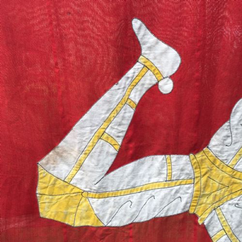 fig 2. A 1930s red cotton flag featuring the stitched white and yellow Triskelion emblem of the Isle of Man.