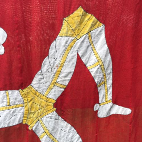 fig 3. A 1930s red cotton flag featuring the stitched white and yellow Triskelion emblem of the Isle of Man.