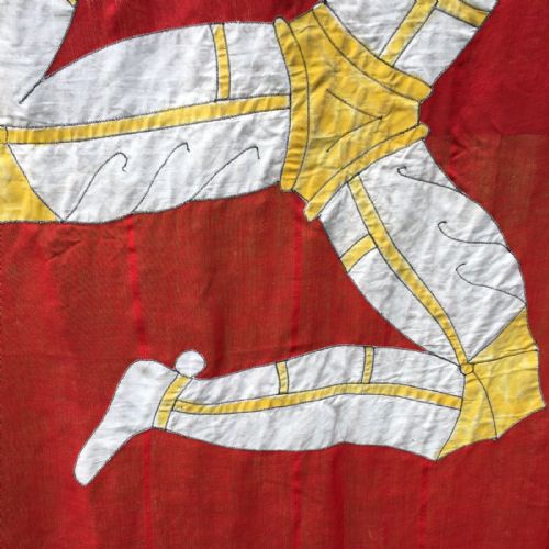 fig 4. A 1930s red cotton flag featuring the stitched white and yellow Triskelion emblem of the Isle of Man.