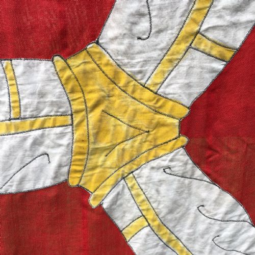 fig 5. A 1930s red cotton flag featuring the stitched white and yellow Triskelion emblem of the Isle of Man.