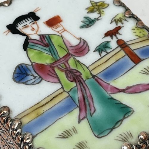 fig 1. A small rectangular silver-plated metal pill box with intricately chased foliate sides and a hand-painted enamel lid depicting a figure in green traditional dress.