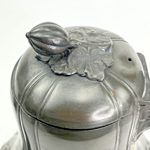fig 5. A dark grey Victorian Britannia metal hot water pot featuring a high gooseneck spout, leaf-lobed body, scroll handle, and floral bud finial.