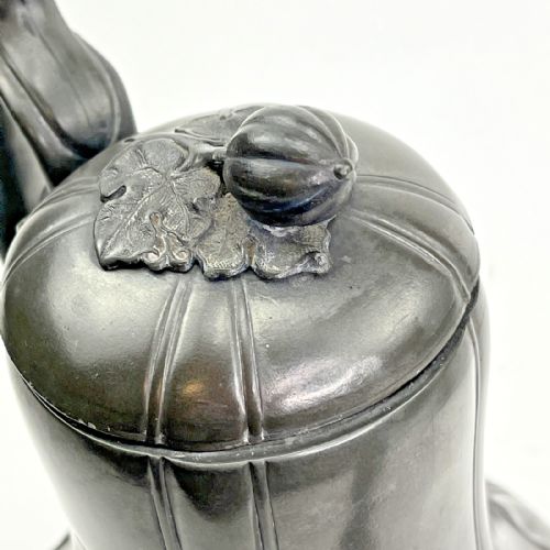 fig 6. A dark grey Victorian Britannia metal hot water pot featuring a high gooseneck spout, leaf-lobed body, scroll handle, and floral bud finial.