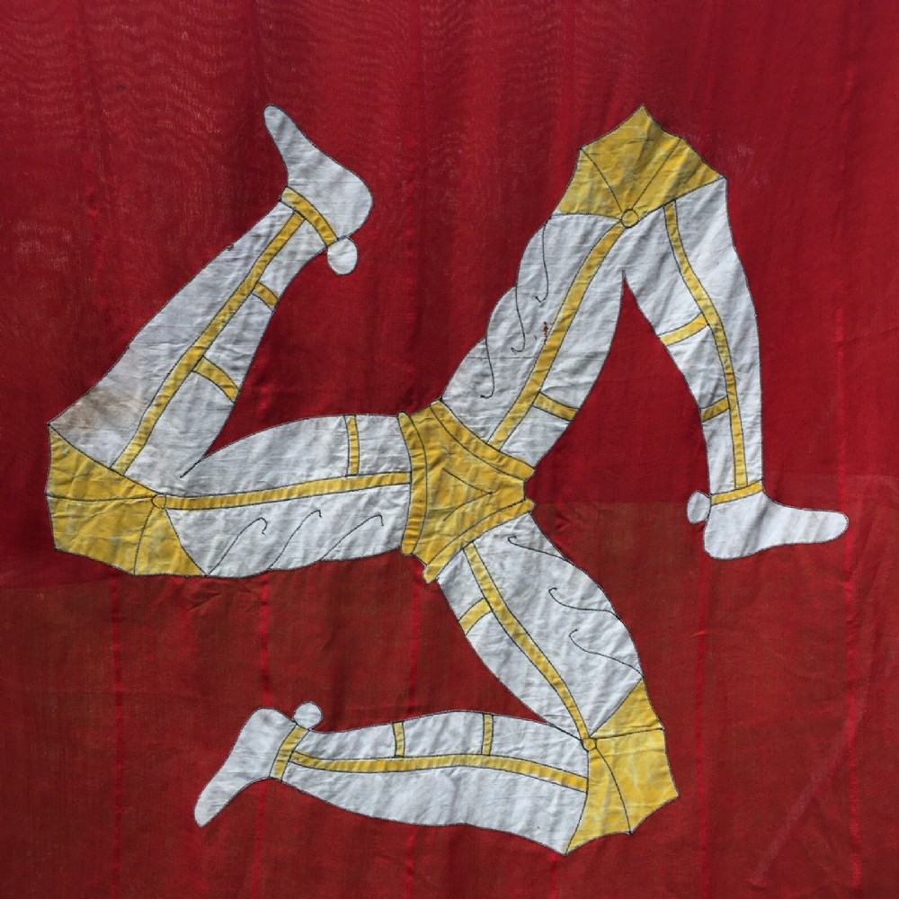 A 1930s red cotton flag featuring the stitched white and yellow Triskelion emblem of the Isle of Man.