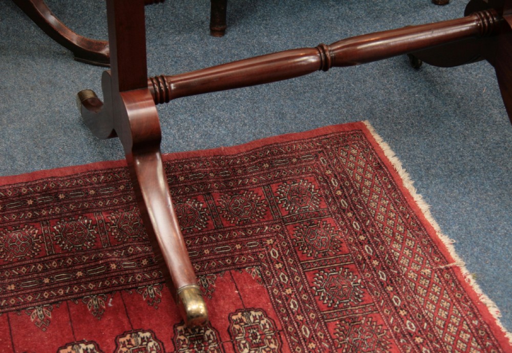 A Regency mahogany cheval mirror featuring an oval pivoting glass within a rectangular frame, supported by turned uprights and splayed legs with brass castors. View II