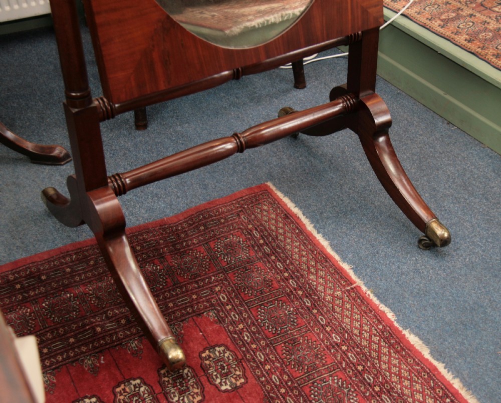 A Regency mahogany cheval mirror featuring an oval pivoting glass within a rectangular frame, supported by turned uprights and splayed legs with brass castors. View IV