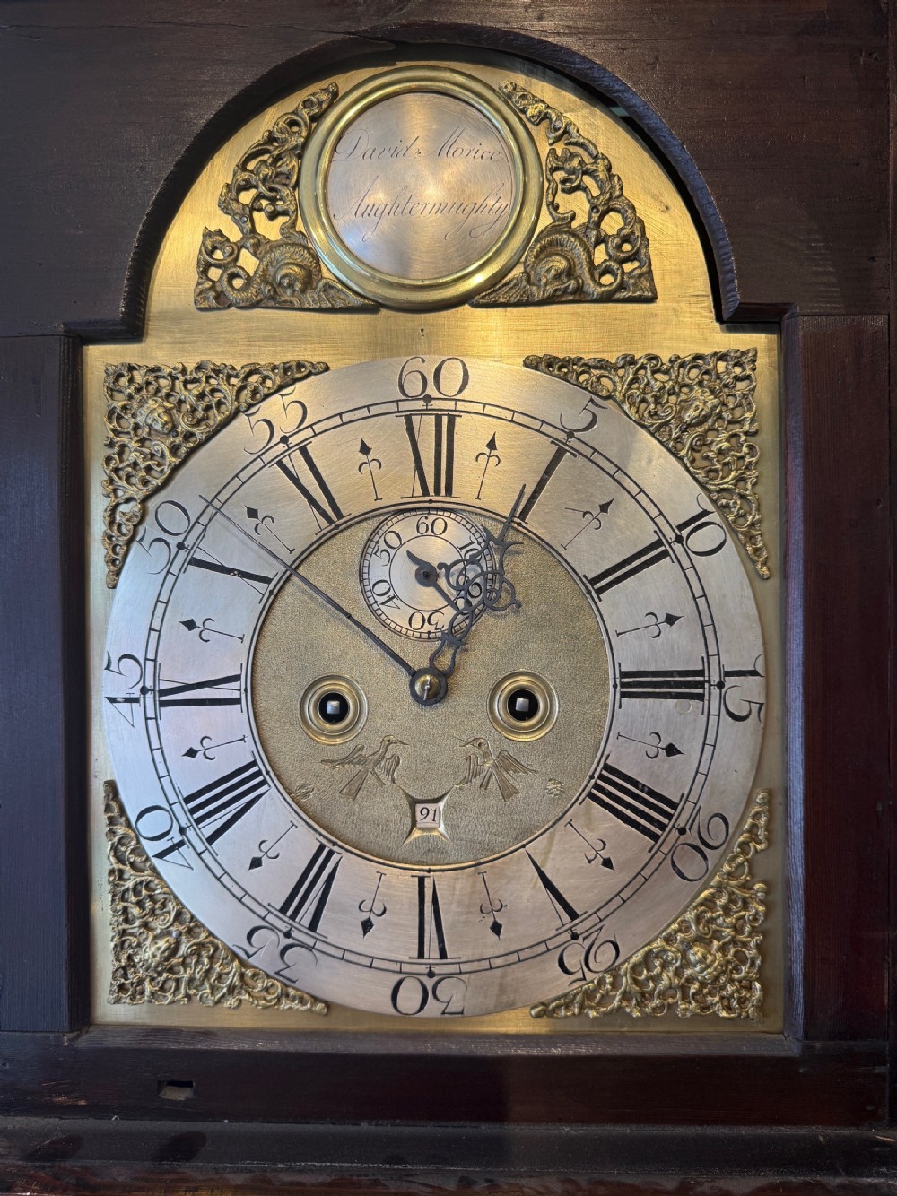An early nineteenth-century Scottish mahogany longcase clock featuring an arched brass dial, urn inlay on the trunk door, and a molded pedestal base. View II