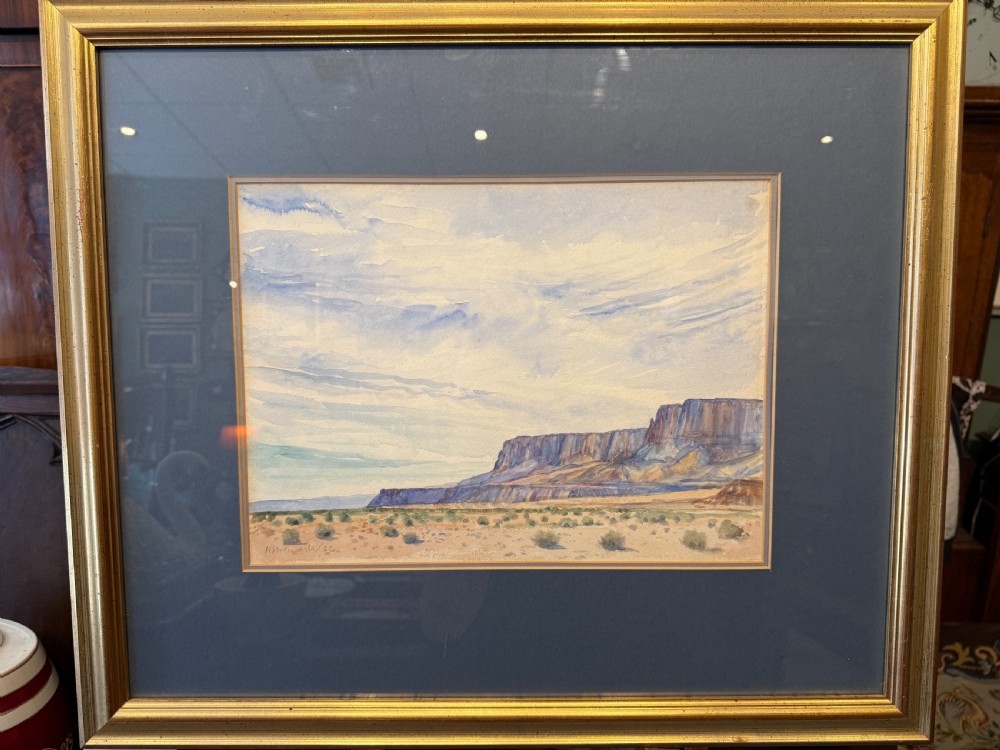 A framed watercolour painting depicting an expansive desert plain leading towards distant rock formations under a light blue sky. View II