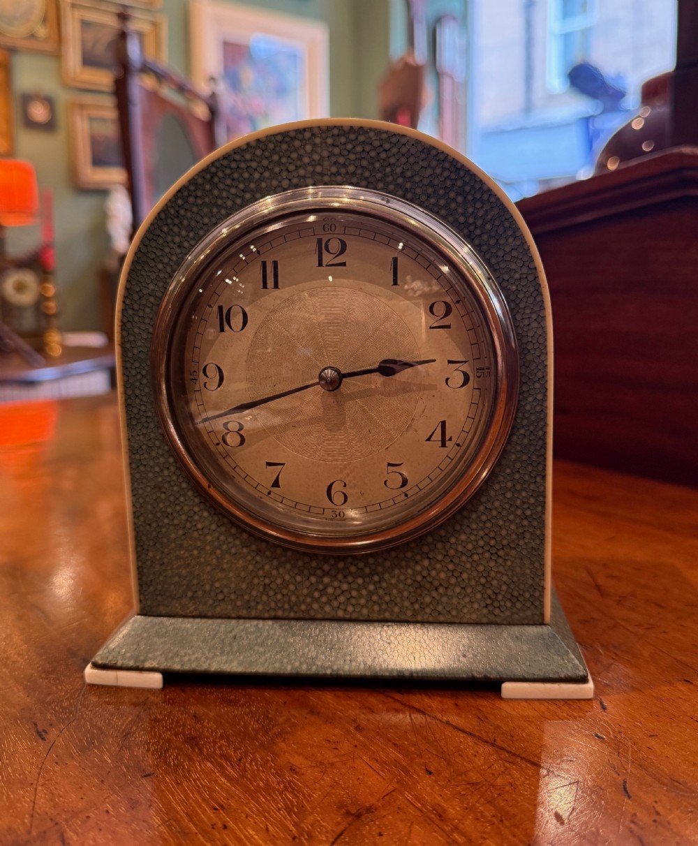 An Art Deco arched table clock clad in green shagreen with ivorine trim, a silvered dial, and black Arabic numerals. View II