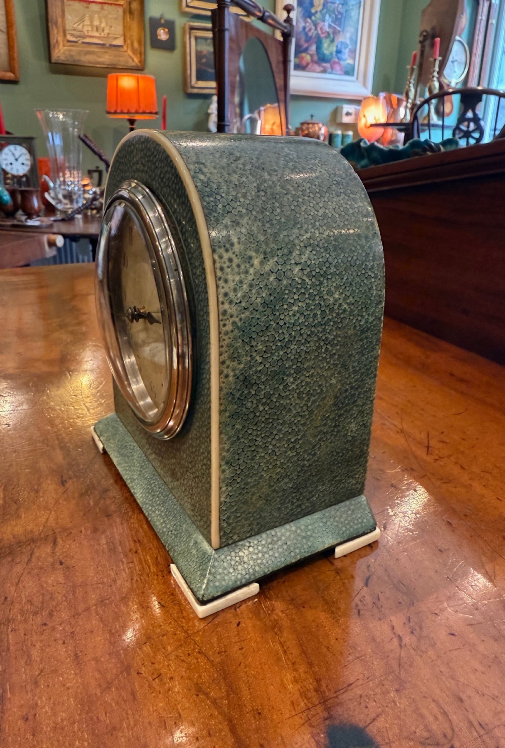 An Art Deco arched table clock clad in green shagreen with ivorine trim, a silvered dial, and black Arabic numerals. View III