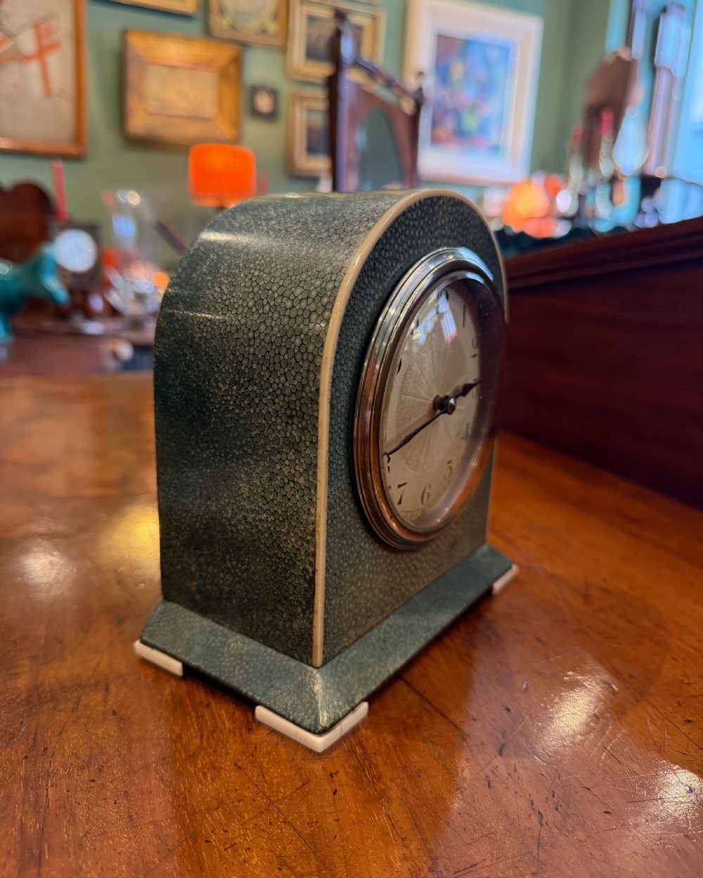 An Art Deco arched table clock clad in green shagreen with ivorine trim, a silvered dial, and black Arabic numerals. View IV