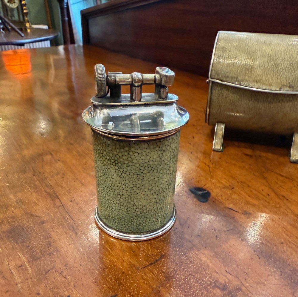 An Art Deco smoking set comprising a sage green shagreen cylindrical table lighter with silver metal fittings alongside a cream shagreen domed cigarette box resting on four small silver feet. View III