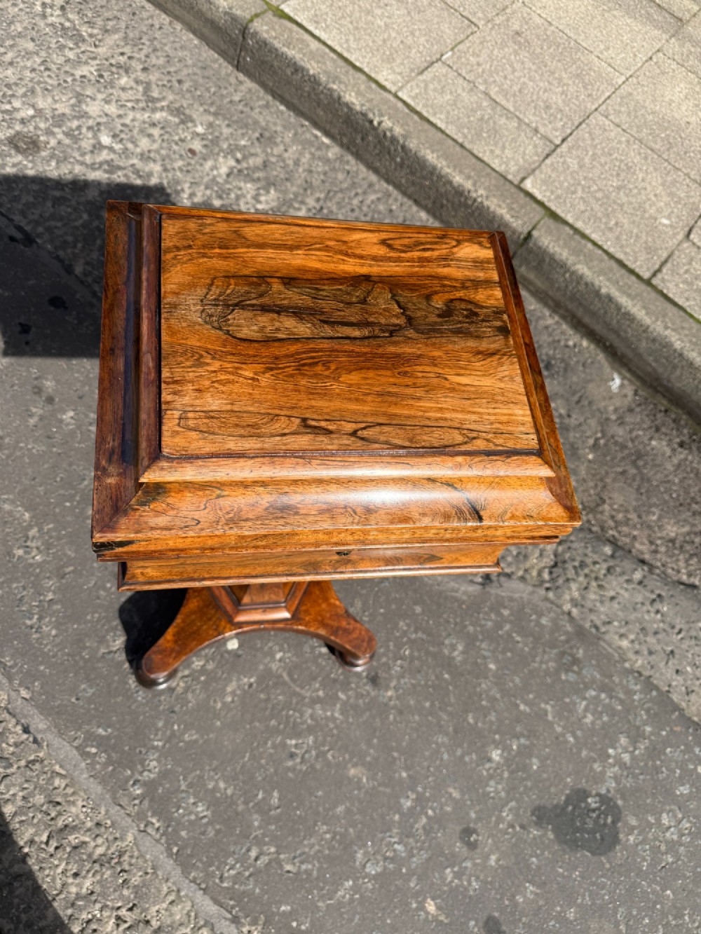 A Regency rosewood teapoy featuring a sarcophagus-shaped hinged lid, faceted pedestal column, and quadripartite plinth base on bun feet. View II