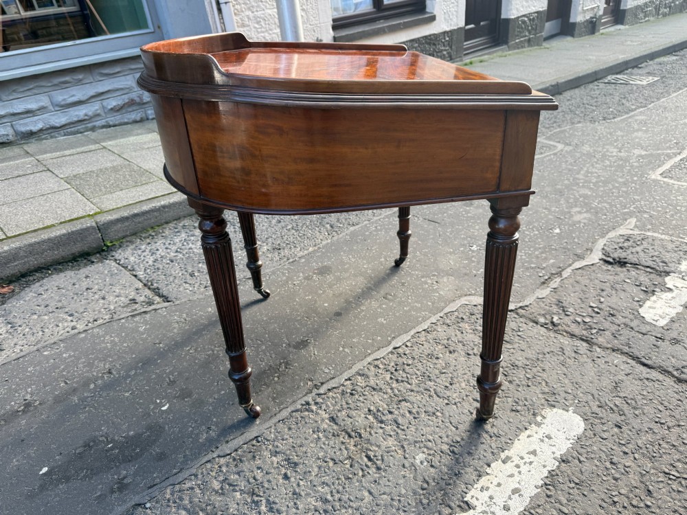 A Mid-Victorian mahogany writing desk featuring a low three-sided gallery top, two frieze drawers with brass drop handles, and reeded tapered legs on castors. View II