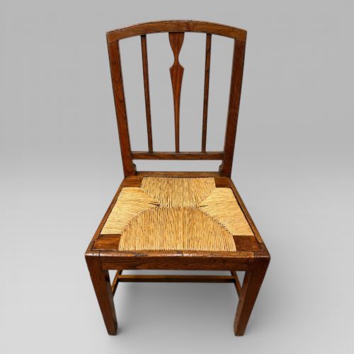 fig 1. A 19th-century elm side chair featuring a woven rush seat, vertical back slats, and straight legs connected by stretchers.