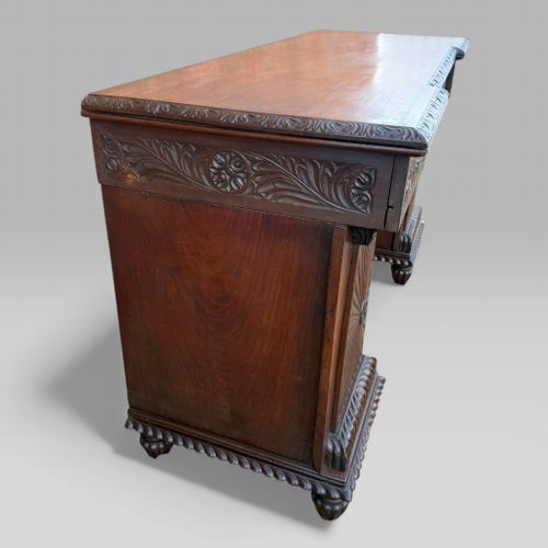 fig 4. A dark carved padouk wood sideboard featuring intricate floral frieze carvings, sunburst panel pedestals, and a central kneehole design.
