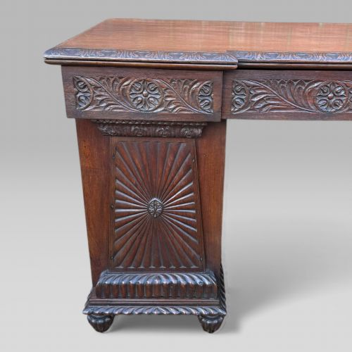 fig 5. A dark carved padouk wood sideboard featuring intricate floral frieze carvings, sunburst panel pedestals, and a central kneehole design.