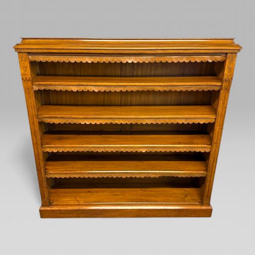 fig 1. A late Victorian open bookcase crafted from golden oak, featuring scalloped edging along each shelf and subtle geometric carvings on the pilasters.