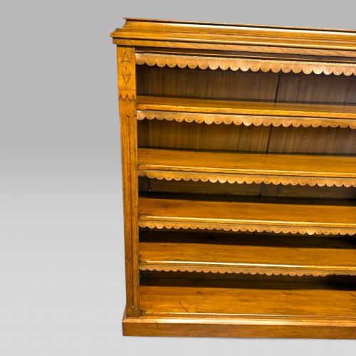 fig 2. A late Victorian open bookcase crafted from golden oak, featuring scalloped edging along each shelf and subtle geometric carvings on the pilasters.